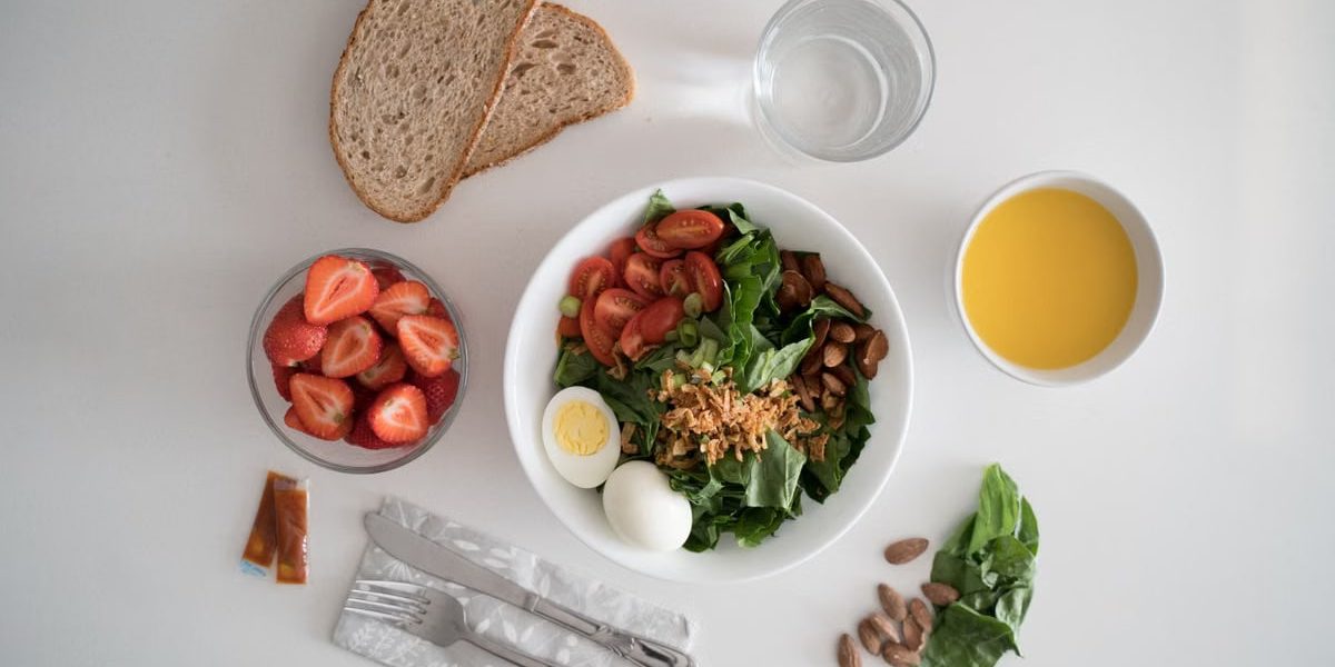 Top view of a nutritious breakfast with salad, eggs, bread, and juice, perfect for a healthy start.