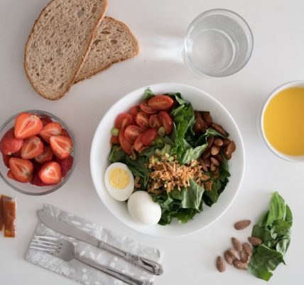 Top view of a nutritious breakfast with salad, eggs, bread, and juice, perfect for a healthy start.