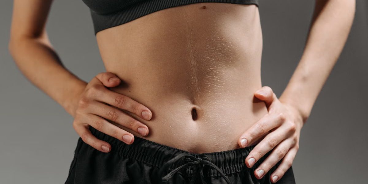 Focused shot of a woman's torso showing athletic physique in a studio setting.